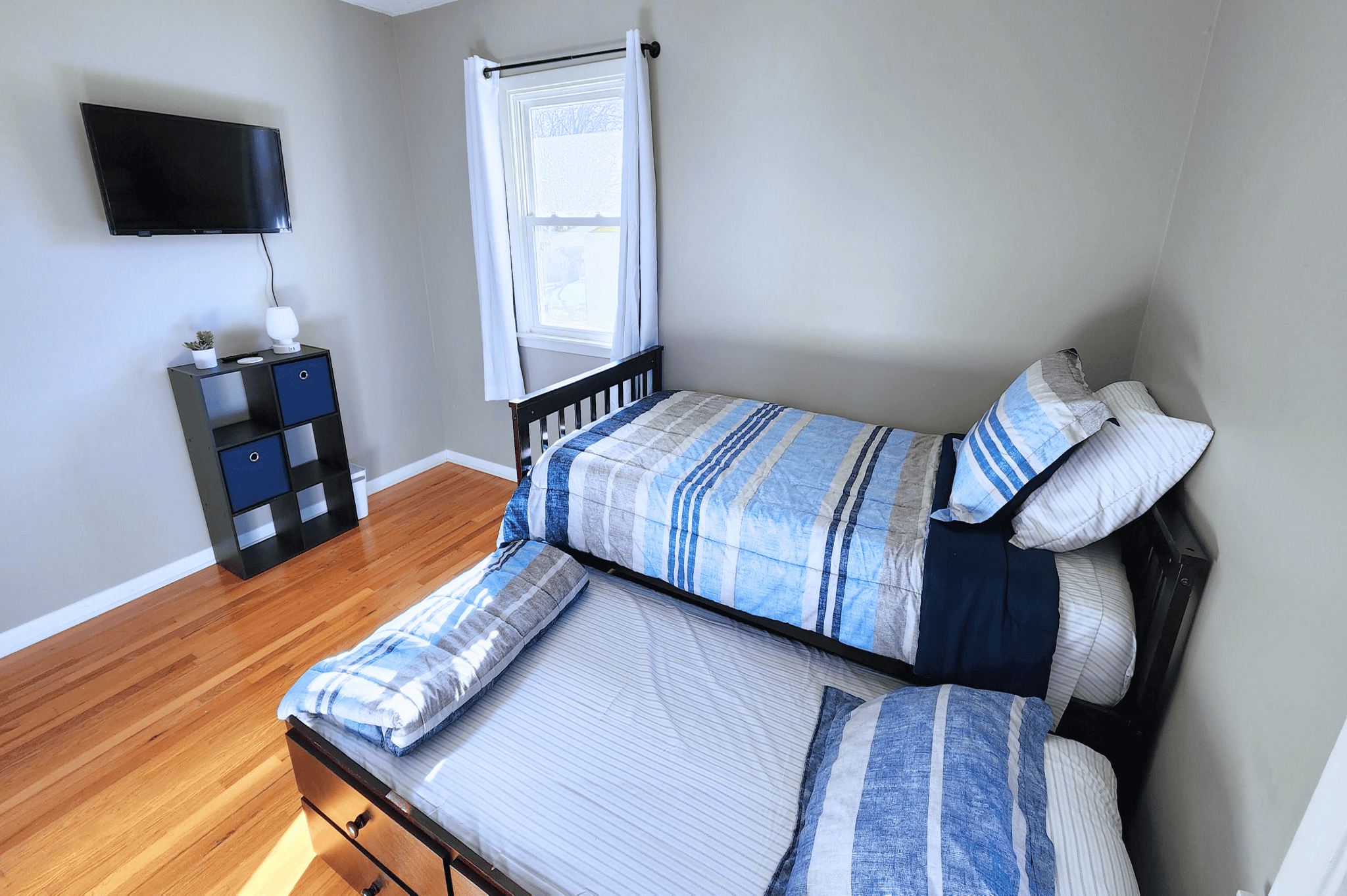 Dining Room Lees Summit Comfortable bedroom featuring a wall-mounted TV, a window with natural light, and a neatly made bed.